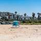 Blue lifeguard tower standing on the sandy beach with coastal buildings, palm trees, and hills under Blue lifeguard tower standing on the sandy beach with coastal buildings, palm trees, and hills under - PhotoDune Item for Sale
