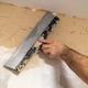 Precision trowel applying finishing plaster to wall surface in residential renovation Precision trowel applying finishing plaster to wall surface in residential renovation - PhotoDune Item for Sale