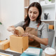 Small business owner preparing customer orders by packing boxes, checking products, recording shipme Small business owner preparing customer orders by packing boxes, checking products, recording shipme - PhotoDune Item for Sale