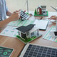 Two colleagues review a digital tablet beside laptops and renewable energy models in a bright modern Two colleagues review a digital tablet beside laptops and renewable energy models in a bright modern - PhotoDune Item for Sale