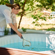 Woman removing leaves from outdoor hot tub with pool skimmer Woman removing leaves from outdoor hot tub with pool skimmer - PhotoDune Item for Sale