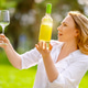 Blonde woman looking at white wine bottle and holding empty clear wineglass in park. Side view of el Blonde woman looking at white wine bottle and holding empty clear wineglass in park. Side view of el - PhotoDune Item for Sale