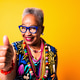 Senior woman giving thumbs up on yellow background Senior woman giving thumbs up on yellow background - PhotoDune Item for Sale
