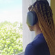 A young African-American woman with headphones on is standing by the window, listening to music and A young African-American woman with headphones on is standing by the window, listening to music and - PhotoDune Item for Sale