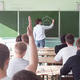 A view from behind a student answering a question during a university lecture. A view from behind a student answering a question during a university lecture. - PhotoDune Item for Sale