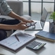 Businessman calculating expenses and reviewing financial statistics using smartphone and laptop. Businessman calculating expenses and reviewing financial statistics using smartphone and laptop. - PhotoDune Item for Sale