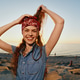 Smiling Woman With Red Bandana and Denim Outfit Posing Joyfully on Rocky Beach During Golden Hour Smiling Woman With Red Bandana and Denim Outfit Posing Joyfully on Rocky Beach During Golden Hour - PhotoDune Item for Sale