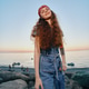 Smiling Woman With Red Bandana Wearing Denim Dress Standing on Rocky Beach at Sunset With Calm Sea Smiling Woman With Red Bandana Wearing Denim Dress Standing on Rocky Beach at Sunset With Calm Sea - PhotoDune Item for Sale
