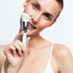Young woman with clear skin holding a white makeup brush near her face, smiling gently. Minimalist Young woman with clear skin holding a white makeup brush near her face, smiling gently. Minimalist - PhotoDune Item for Sale