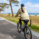 Woman riding bicycle by the sea. Vertical coastal travel scene. Woman riding bicycle by the sea. Vertical coastal travel scene. - PhotoDune Item for Sale