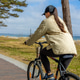 Woman cycling on coastal path. Close seaside recreation view. Woman cycling on coastal path. Close seaside recreation view. - PhotoDune Item for Sale