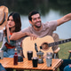Friend, camp, guitar, picnic group relaxing by lake with hat and drink Friend, camp, guitar, picnic group relaxing by lake with hat and drink - PhotoDune Item for Sale