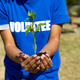 Volunteer holding young plant for environmental restoration Volunteer holding young plant for environmental restoration - PhotoDune Item for Sale
