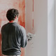 A Caucasian young man is putting putty on the wall. A Caucasian young man is putting putty on the wall. - PhotoDune Item for Sale