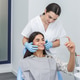 Dentist shows patient results in mirror during dental appointment in bright clinic Dentist shows patient results in mirror during dental appointment in bright clinic - PhotoDune Item for Sale
