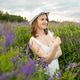 Woman in white dress and hat standing in blooming flower field. Summer outdoor portrait of girl hold Woman in white dress and hat standing in blooming flower field. Summer outdoor portrait of girl hold - PhotoDune Item for Sale