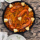 Overhead shot of a traditional Spanish paella with fresh lemons and plates on a table Overhead shot of a traditional Spanish paella with fresh lemons and plates on a table - PhotoDune Item for Sale