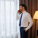 Smiling businessman making phone call by hotel room window in formal suit Smiling businessman making phone call by hotel room window in formal suit - PhotoDune Item for Sale