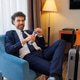 Smiling businessman sitting in hotel room chair opening water bottle after arrival Smiling businessman sitting in hotel room chair opening water bottle after arrival - PhotoDune Item for Sale
