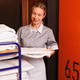Smiling hotel maid carrying fresh bed sheets from housekeeping trolley beside room number sign Smiling hotel maid carrying fresh bed sheets from housekeeping trolley beside room number sign - PhotoDune Item for Sale