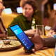 Black Man Using Mobile Payment App While Dining with Friends Black Man Using Mobile Payment App While Dining with Friends - PhotoDune Item for Sale
