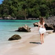 Young woman walking along a tropical beach with clear blue water Young woman walking along a tropical beach with clear blue water - PhotoDune Item for Sale