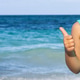 Smiling young girl showing thumbs up at the beach Smiling young girl showing thumbs up at the beach - PhotoDune Item for Sale
