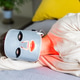 Woman using LED therapy mask while lying on a bed Woman using LED therapy mask while lying on a bed - PhotoDune Item for Sale