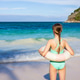 Young girl with swim ring looking at ocean on sunny beach Young girl with swim ring looking at ocean on sunny beach - PhotoDune Item for Sale