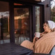 Thoughtful young woman relaxing with warm drink outside modern Scandinavian tiny house Thoughtful young woman relaxing with warm drink outside modern Scandinavian tiny house - PhotoDune Item for Sale