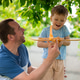 Happy family father and son playing and laughing outside getting toy plane out off tree. Father's da Happy family father and son playing and laughing outside getting toy plane out off tree. Father's da - PhotoDune Item for Sale