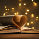Open book with pages curved in heart shape on wooden table against background with blurred lights, c Open book with pages curved in heart shape on wooden table against background with blurred lights, c - PhotoDune Item for Sale