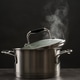 Steaming saucepot on grey table against dark background Steaming saucepot on grey table against dark background - PhotoDune Item for Sale