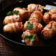 Tasty sausages wrapped in bacon with parsley on wooden table, closeup Tasty sausages wrapped in bacon with parsley on wooden table, closeup - PhotoDune Item for Sale