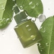 Cosmetic oil in bottle and green leaves on white background, top view through glass surface with dro Cosmetic oil in bottle and green leaves on white background, top view through glass surface with dro - PhotoDune Item for Sale
