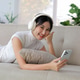 Young Asian woman wearing headphones relaxing on sofa Young Asian woman wearing headphones relaxing on sofa - PhotoDune Item for Sale