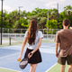 Young couple entering outdoor pickleball court. Man holds paddle and points. Active lifestyle, healt Young couple entering outdoor pickleball court. Man holds paddle and points. Active lifestyle, healt - PhotoDune Item for Sale