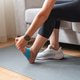 Woman massaging foot with kinesiology tape at home Woman massaging foot with kinesiology tape at home - PhotoDune Item for Sale