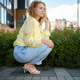 Woman in shirt and jeans crouching in city street during daytime with buildings and plants around Woman in shirt and jeans crouching in city street during daytime with buildings and plants around - PhotoDune Item for Sale