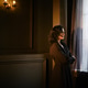 Woman standing by a window looking out on a rainy day in a softly lit room Woman standing by a window looking out on a rainy day in a softly lit room - PhotoDune Item for Sale