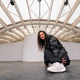 Woman with curly hair squatting, smiling under a contemporary white building structure Woman with curly hair squatting, smiling under a contemporary white building structure - PhotoDune Item for Sale