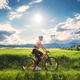 Female cyclist riding mountain bike through vibrant green meadow Female cyclist riding mountain bike through vibrant green meadow - PhotoDune Item for Sale