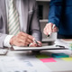 Two men are sitting at a desk with a white board and a stack of papers Two men are sitting at a desk with a white board and a stack of papers - PhotoDune Item for Sale