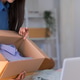 Young Asian woman unpacking cardboard box while managing online merchant business at home office wit Young Asian woman unpacking cardboard box while managing online merchant business at home office wit - PhotoDune Item for Sale
