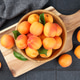Fresh Ripe Organic Apricots Fruits In Wooden Bowl On Cutting Board Over Black Tile Background Fresh Ripe Organic Apricots Fruits In Wooden Bowl On Cutting Board Over Black Tile Background - PhotoDune Item for Sale