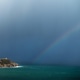 Storm clouds with rainbows approach a lighthouse on the rocky coast Storm clouds with rainbows approach a lighthouse on the rocky coast - PhotoDune Item for Sale