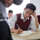 Tired Asian High School Student Resting His Head on His Hand While Writing in Classroom Exam Tired Asian High School Student Resting His Head on His Hand While Writing in Classroom Exam - PhotoDune Item for Sale