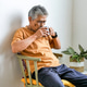 Senior Man Sitting Comfortably on Chair at Home While Drinking From Black Mug Senior Man Sitting Comfortably on Chair at Home While Drinking From Black Mug - PhotoDune Item for Sale