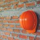 Orange Safety helmet (hard hat) with brick background in construction site. Orange Safety helmet (hard hat) with brick background in construction site. - PhotoDune Item for Sale