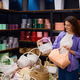 Caucasian woman casually browsing wicker baskets while surrounded by vibrant hat boxes and props Caucasian woman casually browsing wicker baskets while surrounded by vibrant hat boxes and props - PhotoDune Item for Sale
